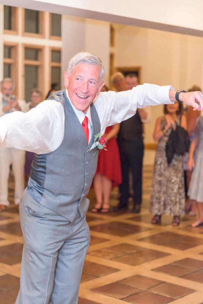 An older man dressed in a suit dances while guests surround him during the open dancing part of the timeline