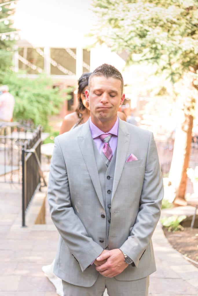 A groom about to turn around and see his bride for the first time. First Looks are a great way to spend more alone time together on your wedding day.