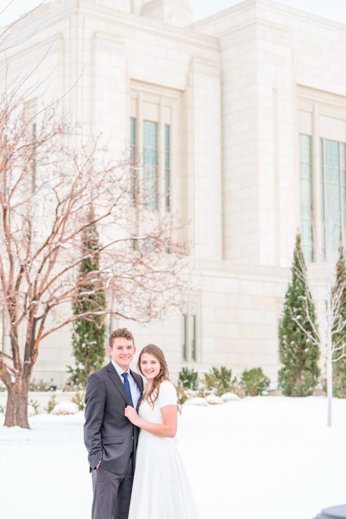 A couple looking their best in the snow. Their wedding day emergency bag is held by the bride’s maid of honor.