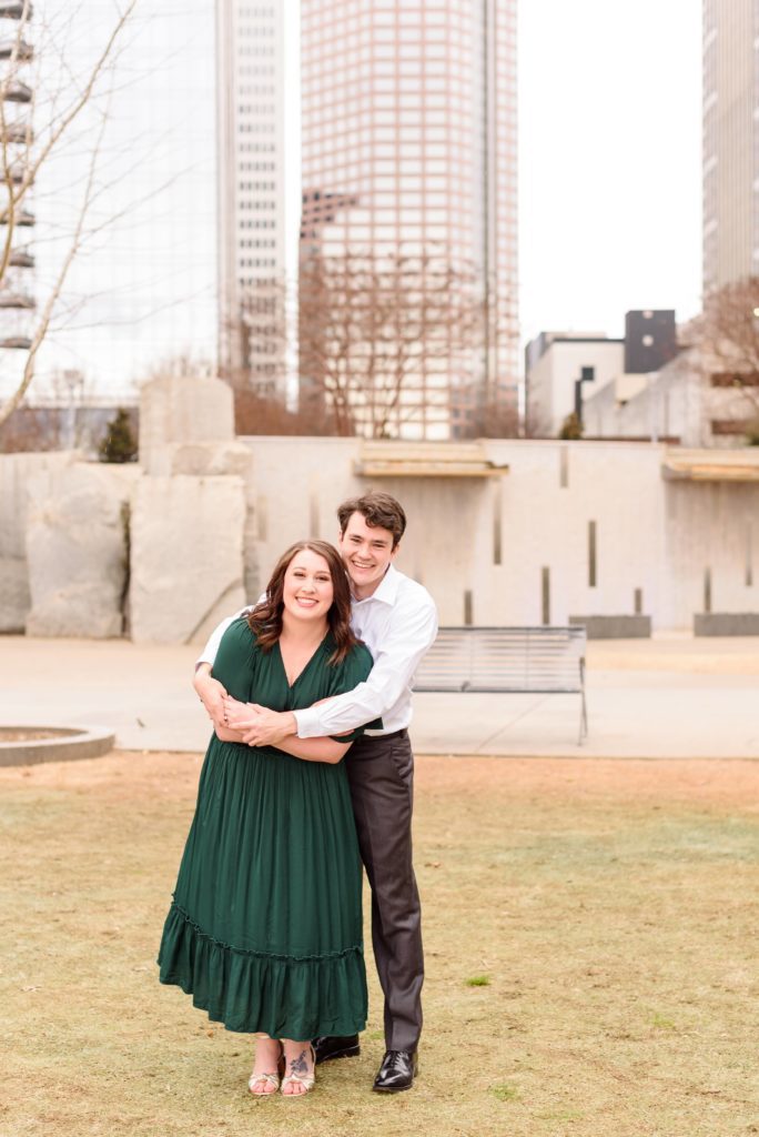 A Charlotte engagement session at Romare Bearden Park. The Charlotte skyline is seen in the distance.