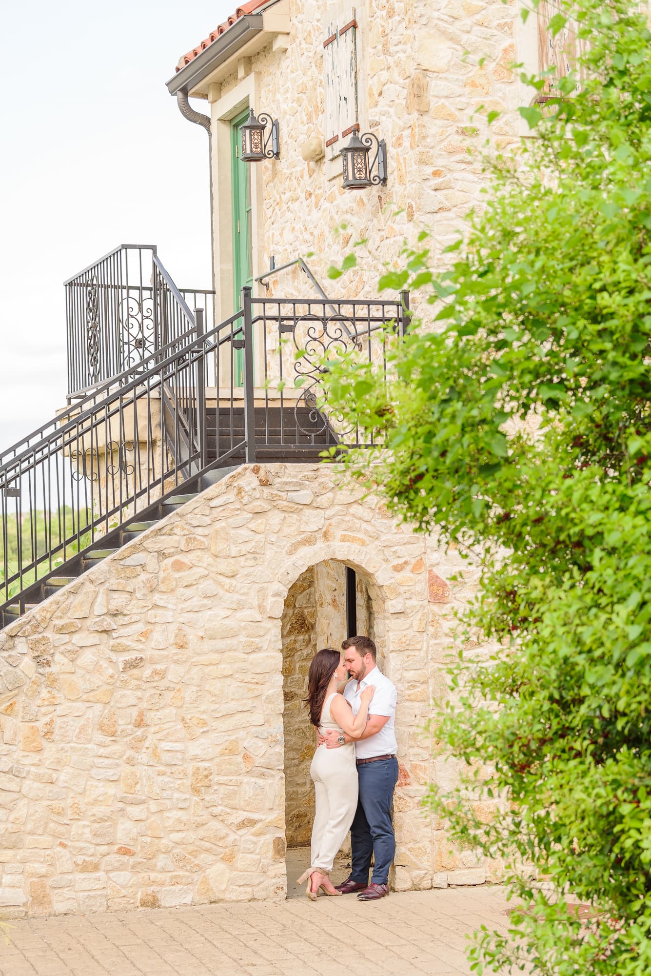 There is a European style building with an arch way and stone walls for this engagement session.