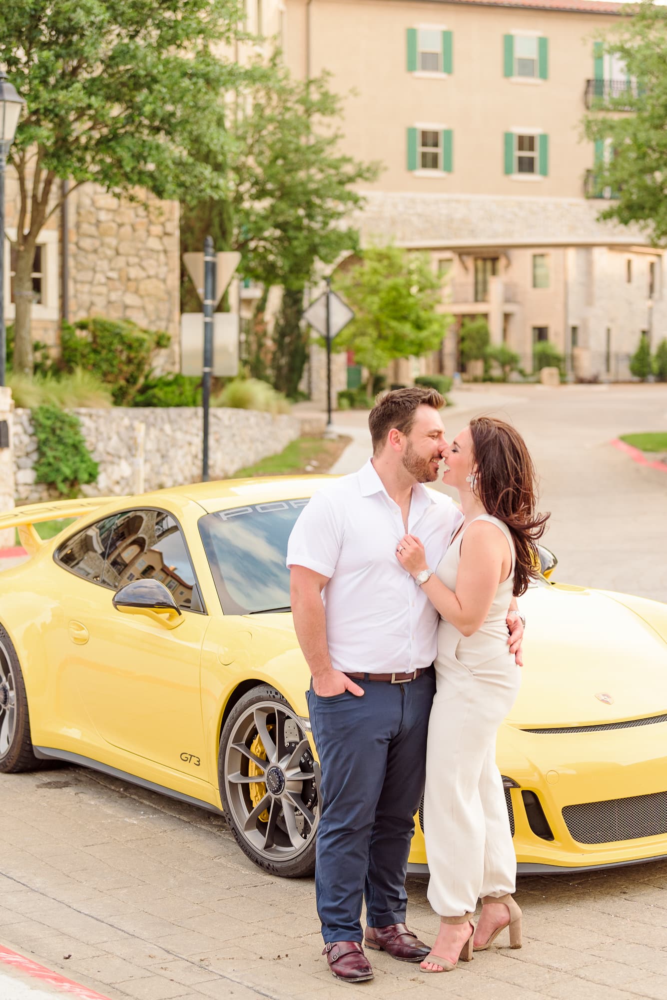A couple stands in front of a yellow sports car at their European style engagement session.