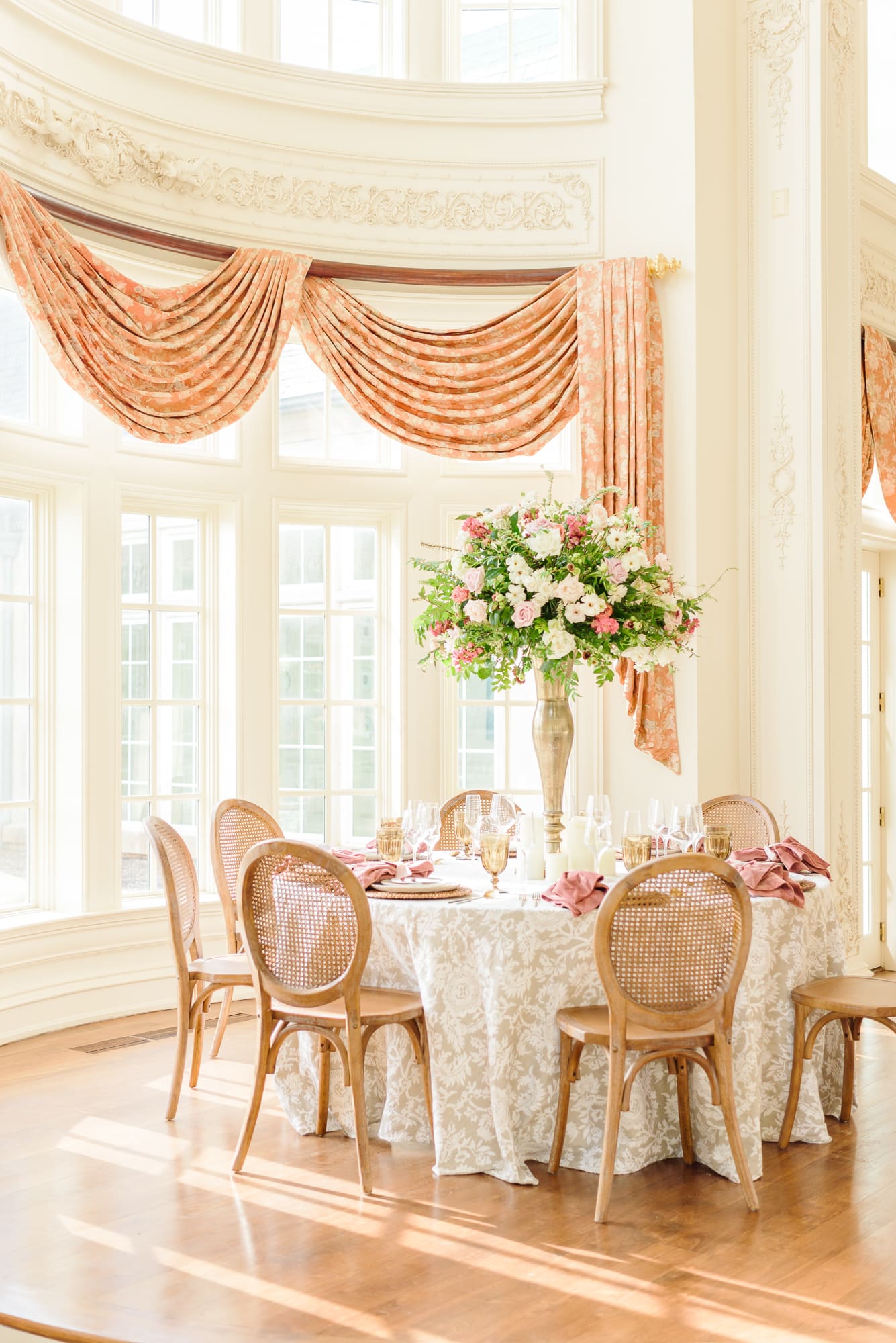 An elegant mansion wedding with a formal table setting in pink and orange.