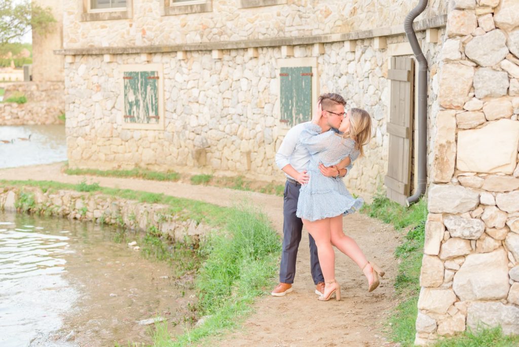 They kiss during their engagement photos next to the river walk.