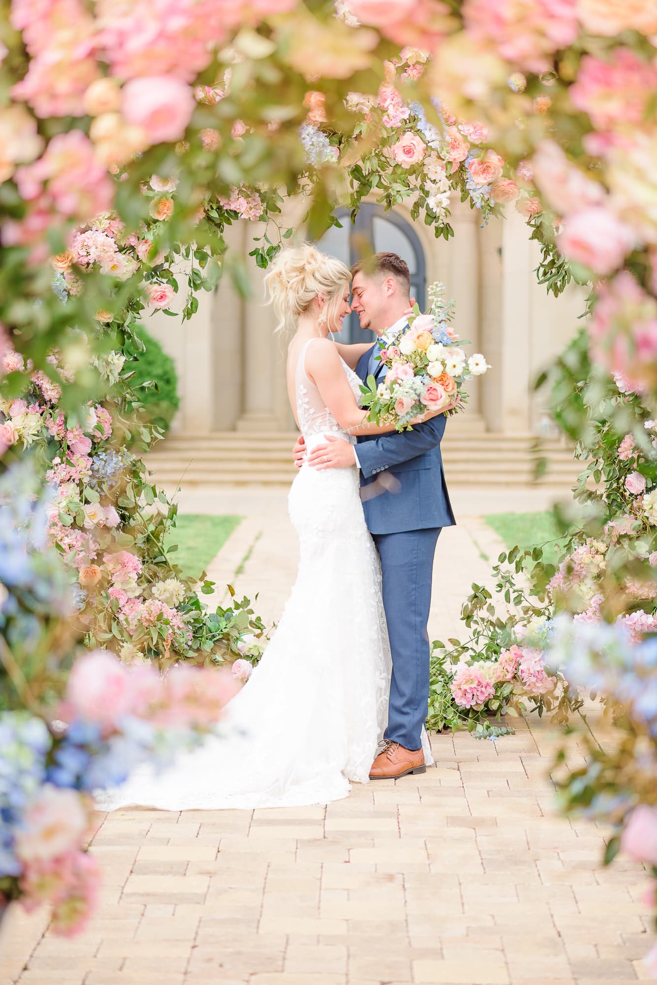 In this photograph, we see a double arch backdrop with flowers at this wedding in summer colors.