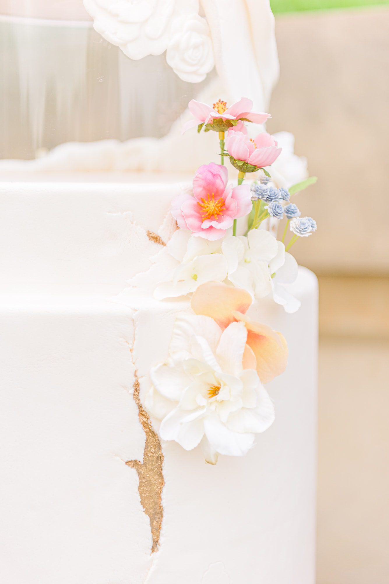 Closeup of a wedding cake decorated with summer colors and edible flowers.