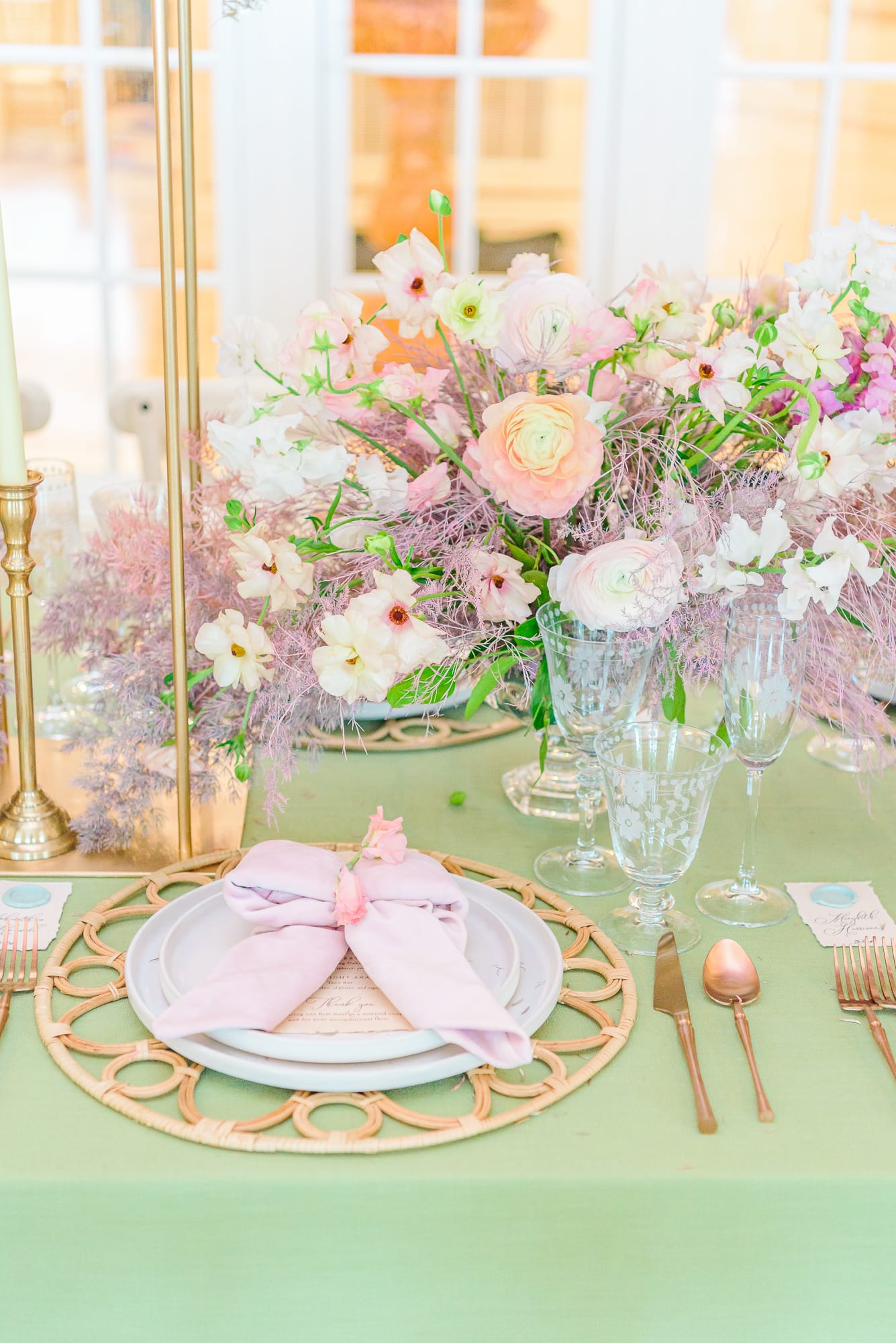 Purple flowers and place settings are designed on green linen at this wedding.