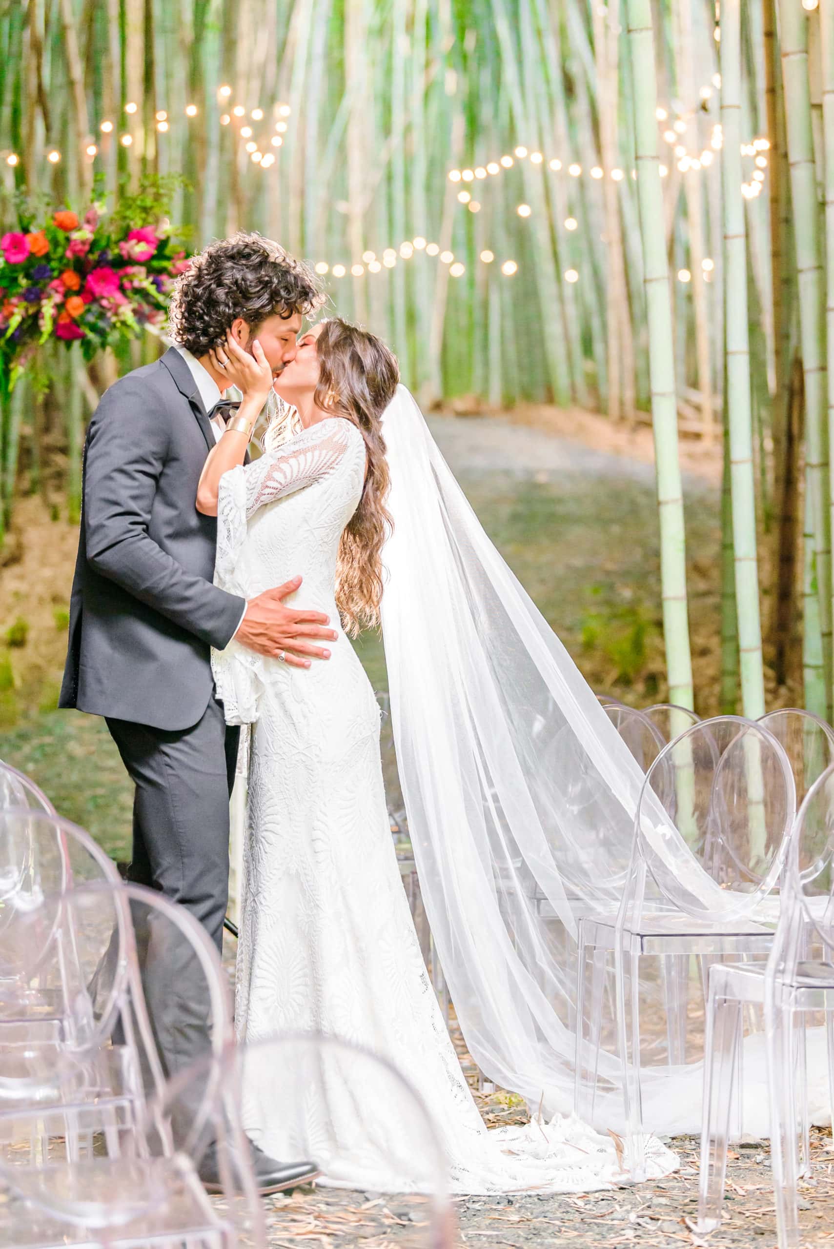 Kaelyn and Trevor kiss as this Belmont wedding venue's bamboo forest stretches behind them, strung with lights.