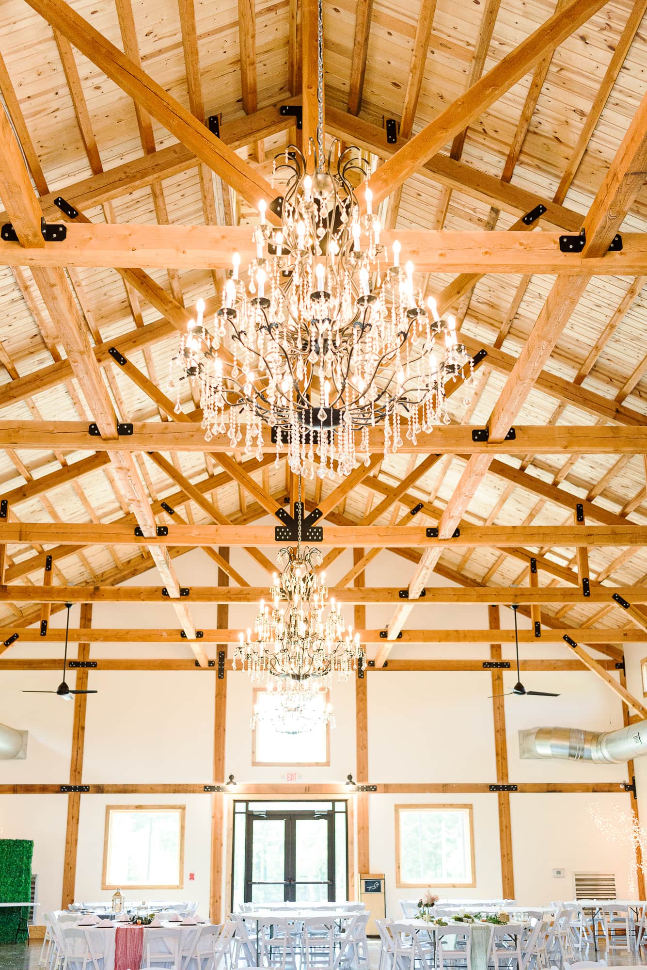 Chandeliers and exposed beams make up the ceiling in the Camelot Meadows hall.