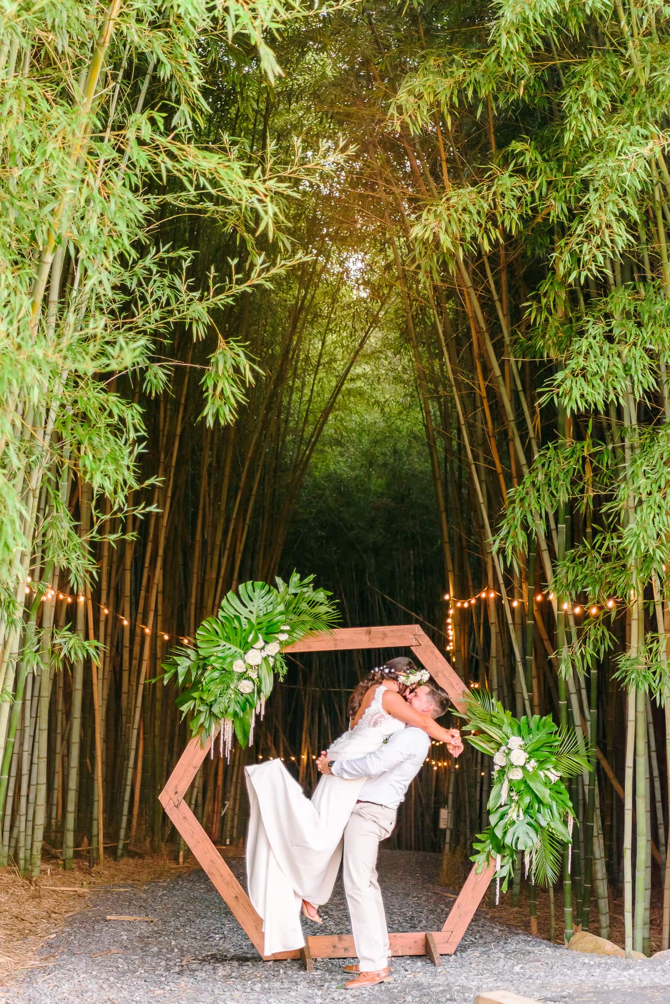 Raycia and Kinston pose in front of the ceremony arch. The Camelot Meadows bamboo forest can be seen behind them.