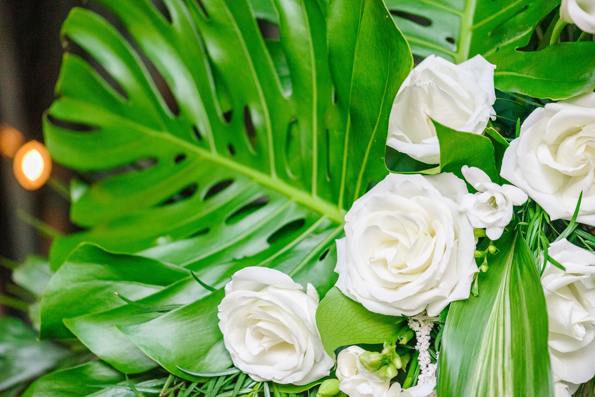 Tropical leaves and white roses make up this bouquet at this Camelot Meadows wedding.