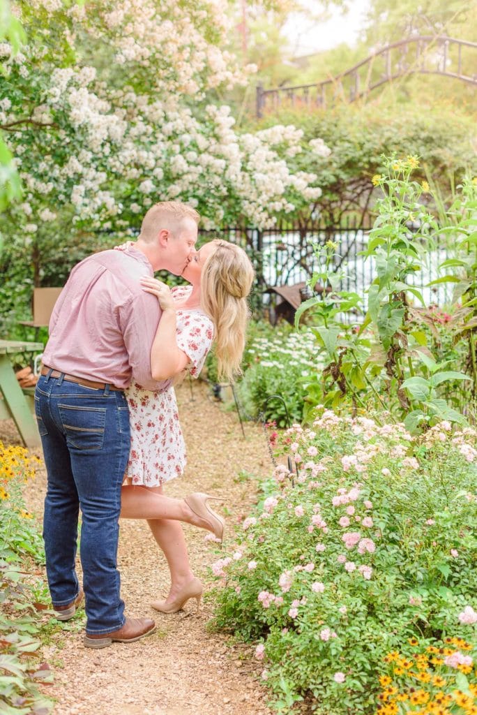 Danielle and Phillip kiss eachother, surrounded by the blooming flowers in this Charlotte Rose Garden.
