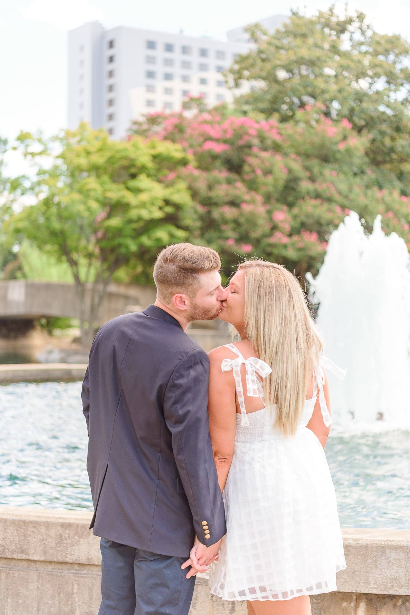 Heather and Corey kiss each other in front of the Marshall Park fountain in uptown Charlotte.