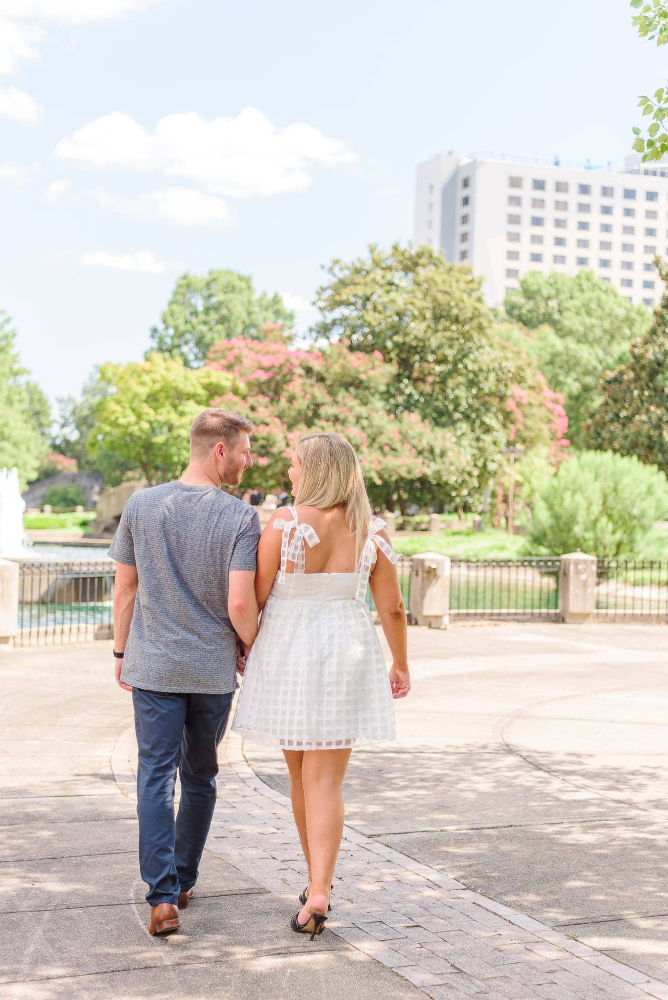 Corey and Heather walk hand in hand through Marshall Park in Charlotte.