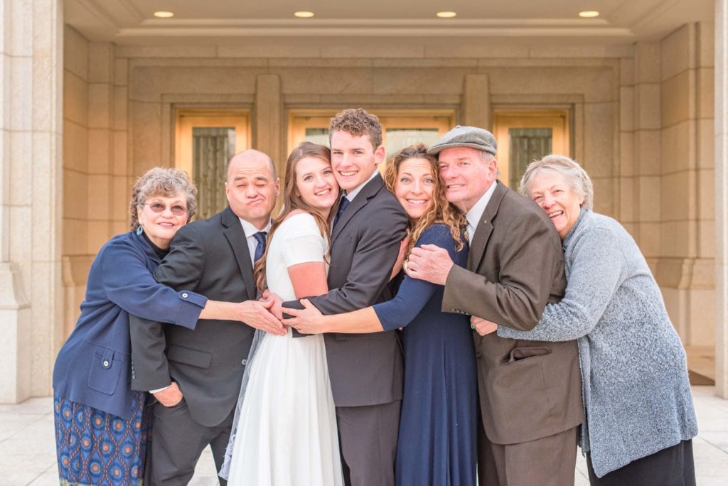 Jennifer and Adam take family photos of everyone hugging at their wedding.