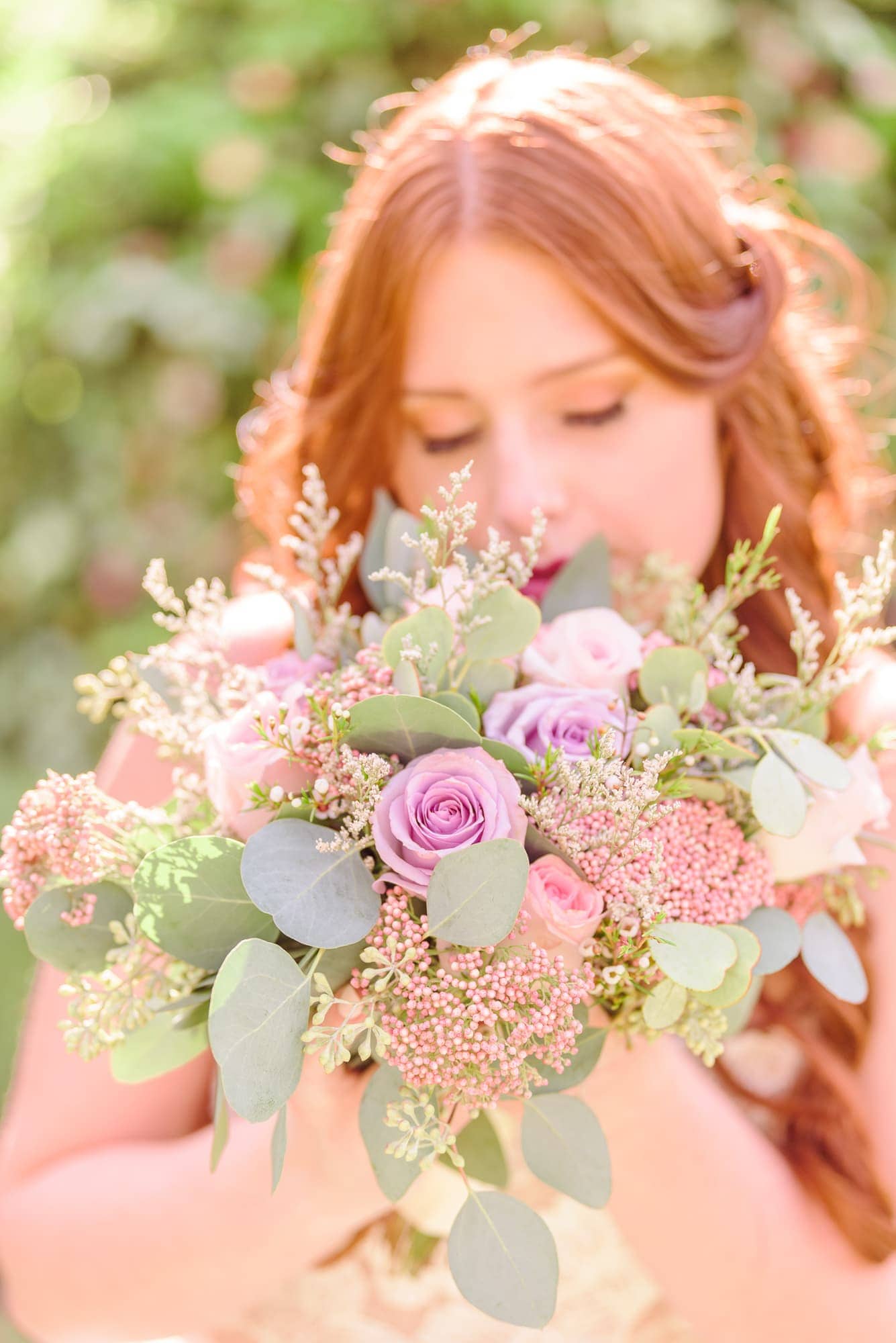 The bride smells her pink and purple bouquet during her photography session at Key Rose Estate in Fayetteville.