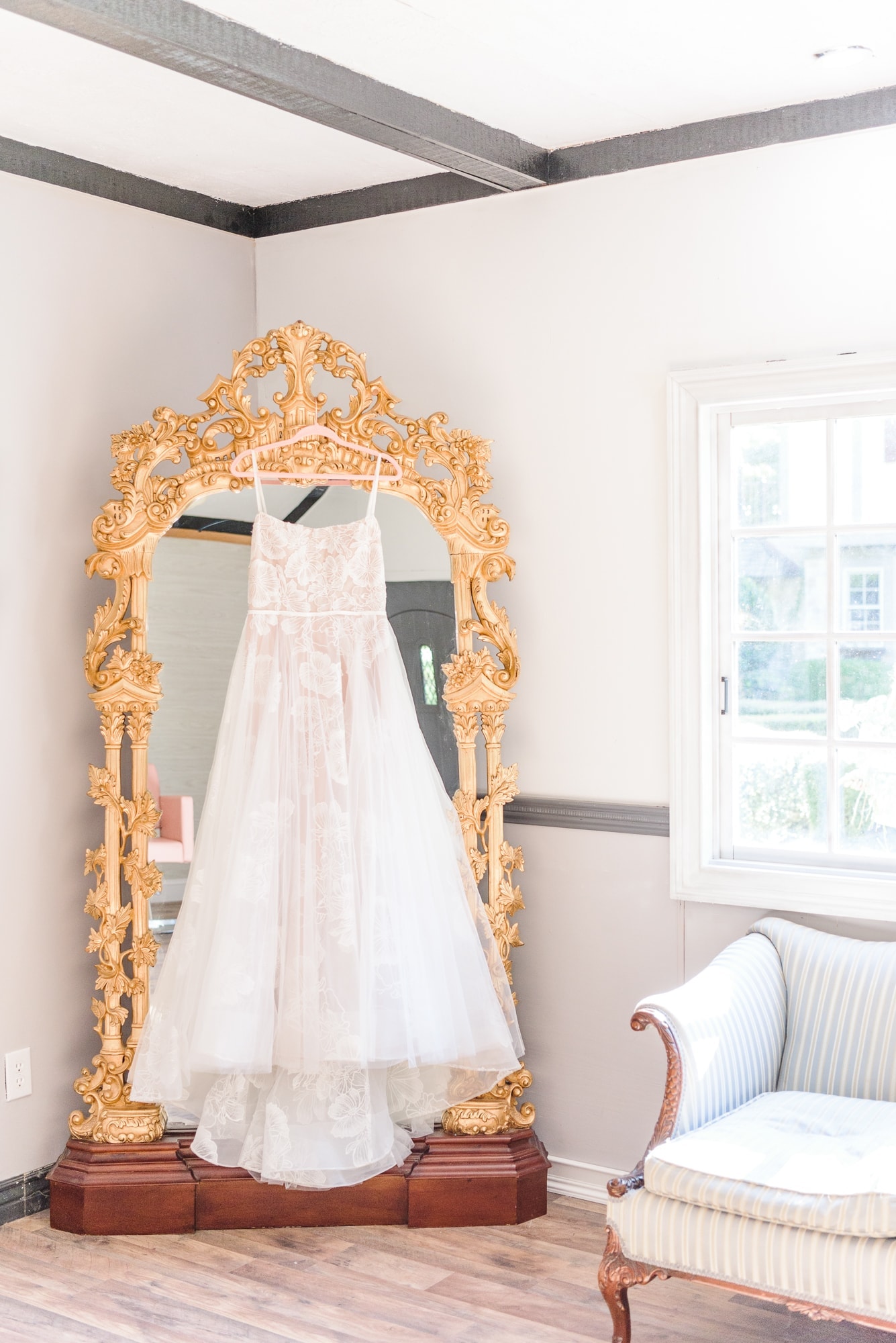 The wedding dress is hung on the Key Rose Estate's ornate gold mirror in the bride's room.