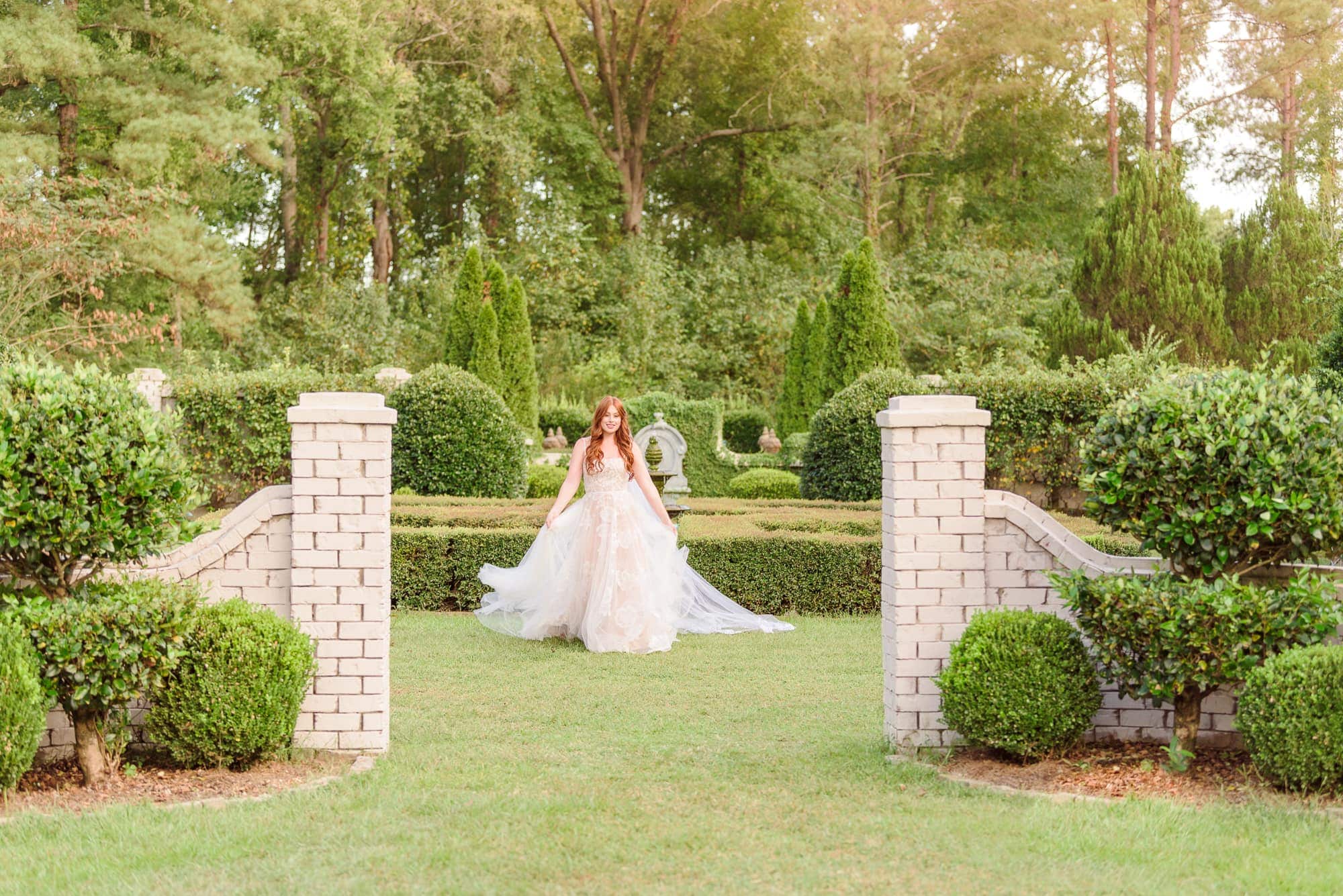 Olivia walks through the white brick gate at Key Rose Estate in Fayetteville.