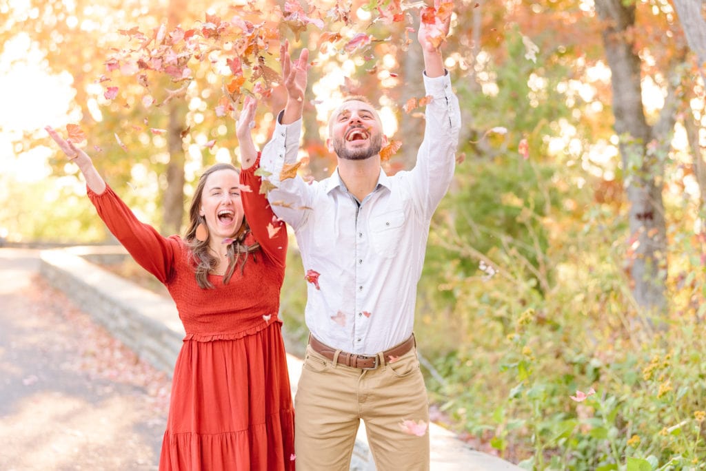 Alicia and Joey throw leaves up in the air during their fall engagement photos at Morrow Mountain in North Carolina.