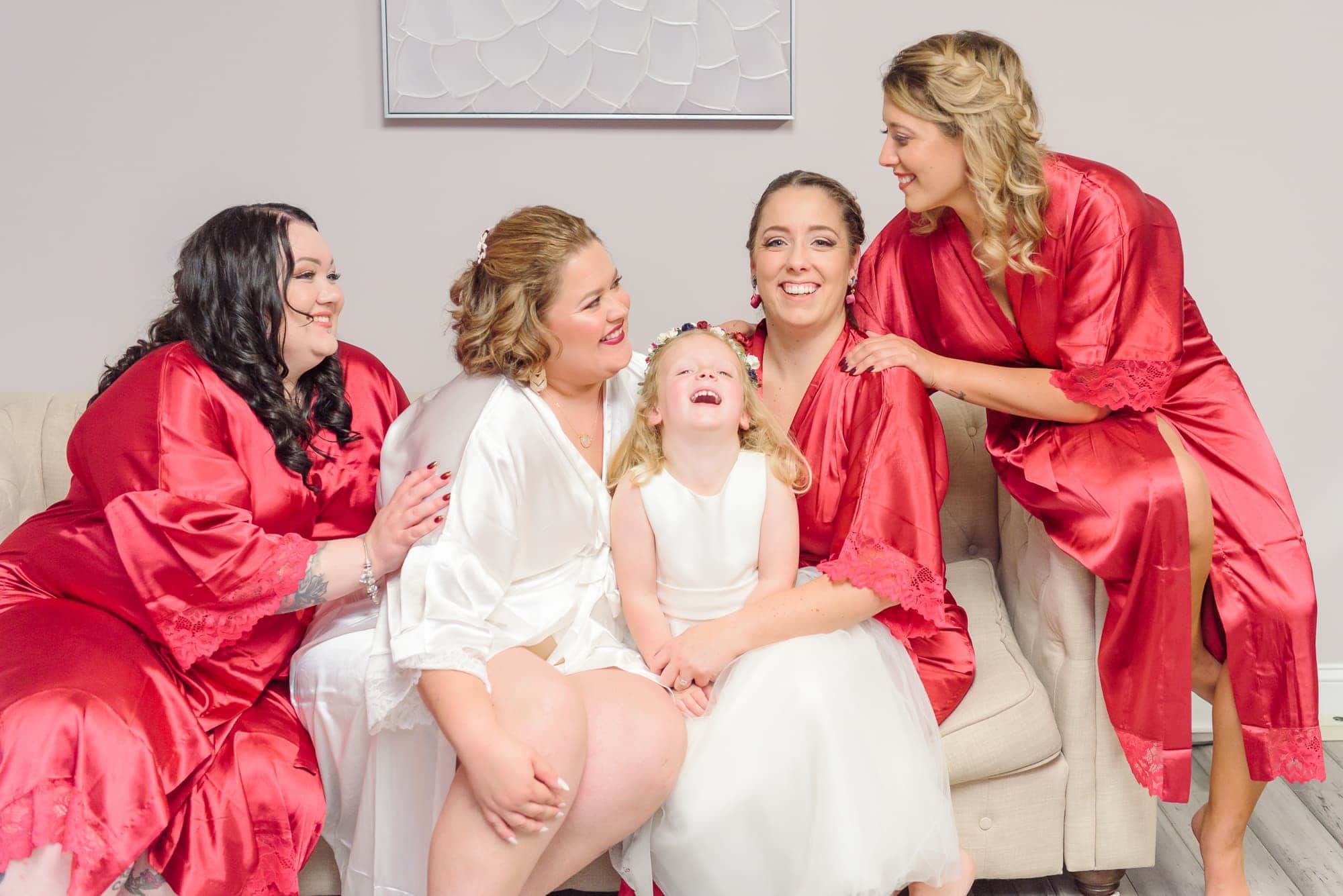 The bridesmaids hug and laugh with one another in matching robes the morning of this wedding at the Charles Mack Citizen Center.