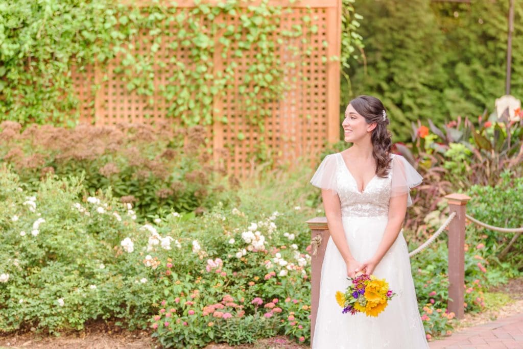 The bride walks down a beautiful garden path at Alexander Homestead during her bridal photos.