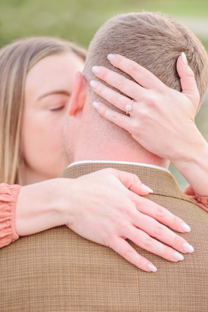 Her classic diamond engagement ring is visible while they take their city engagement photos.