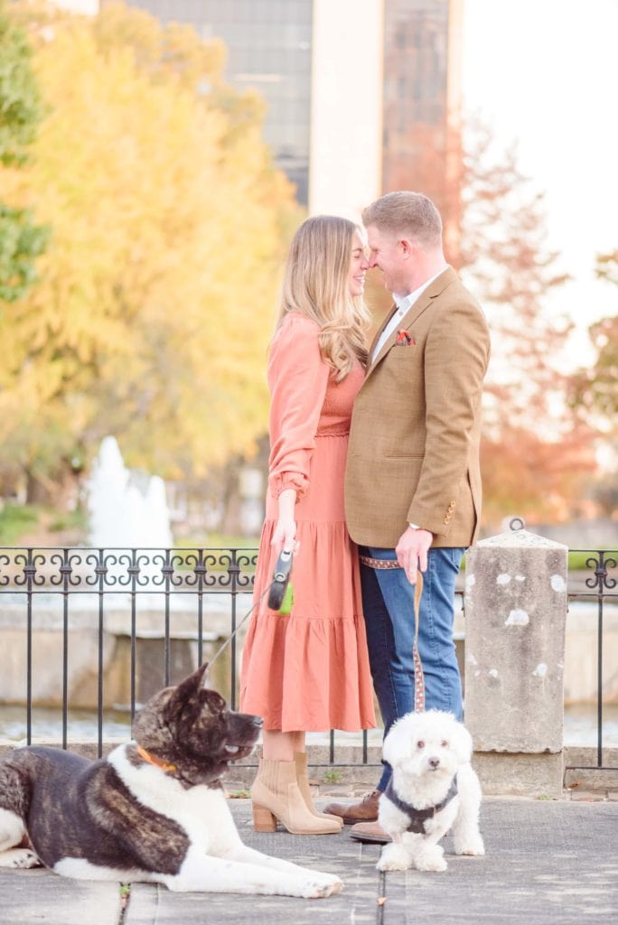 Kati and Curtis stand nose to nose with their dogs for their city engagement photos in Charlotte.