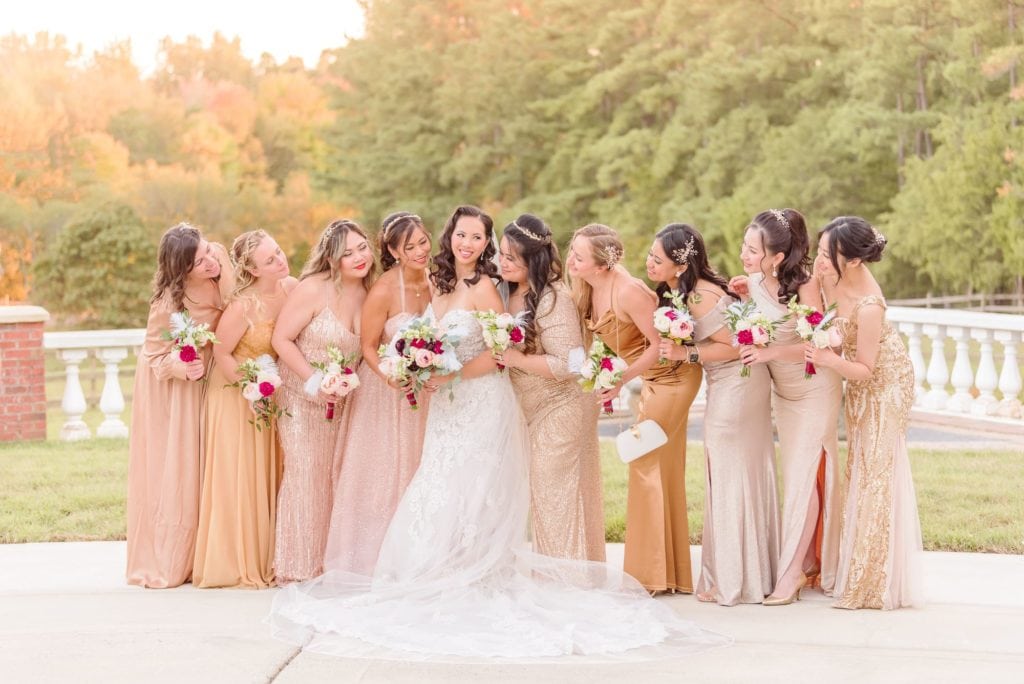 Ashley and her bridesmaids smile at one another on the front lawn at her Hollywood themed wedding.