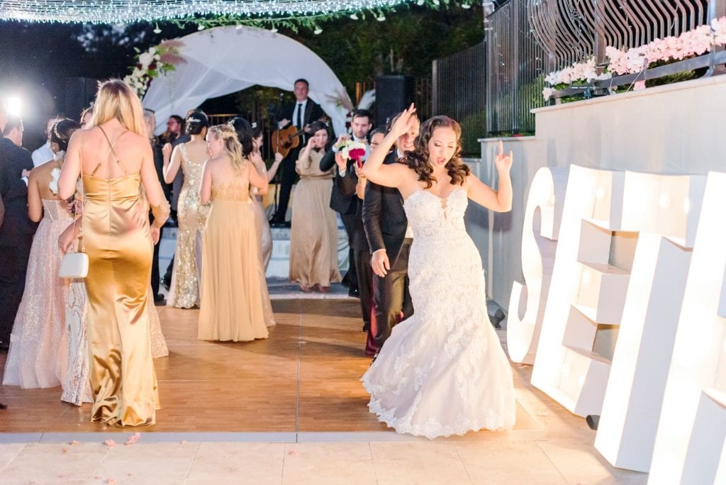 Ashley dances with her hands in the air with Hollywood themed wedding signs reading "Sethley" on the side.
