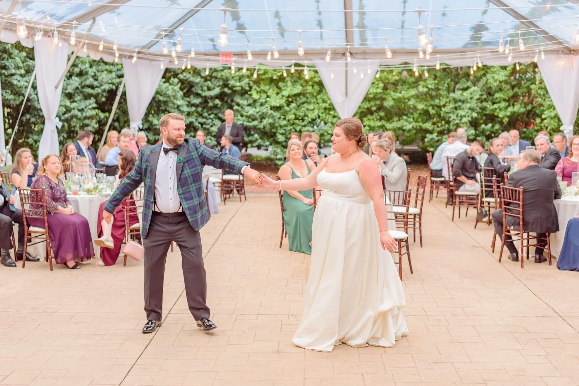String lights hang from the outdoor tent at Whitehead Manor as the bride and groom share an energetic dance together.