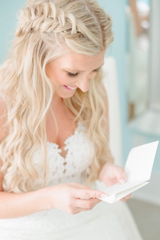 Spencer laughs as she reads a note from Dave before they get married on the beach at this North Carolina wedding.