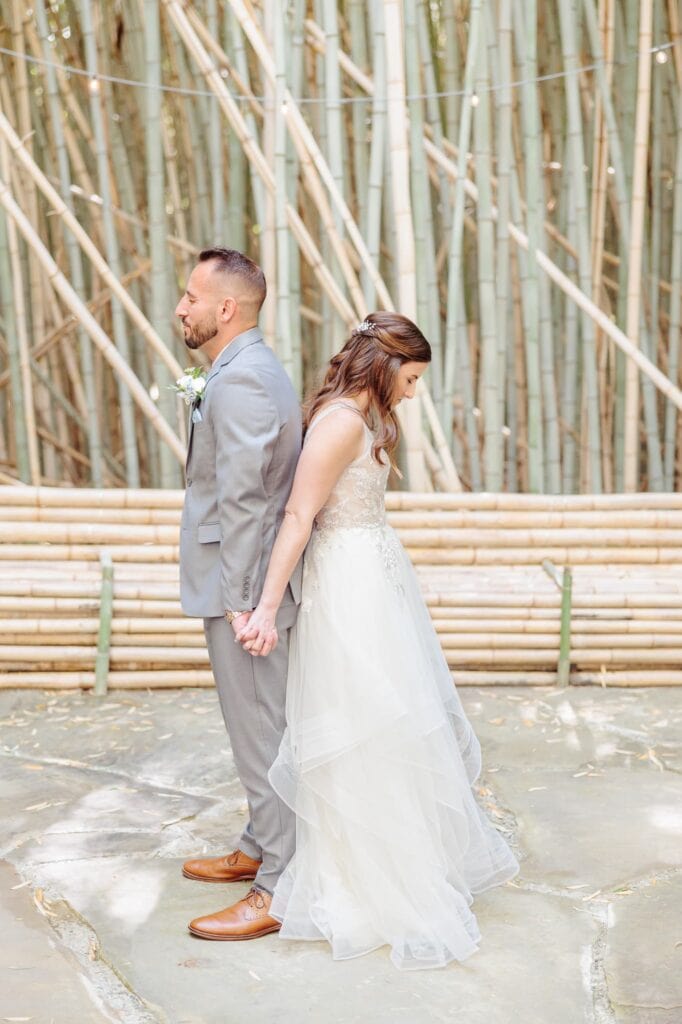 Joey and Alicia stand back to back in the bamboo forest before their outdoor wedding ceremony in North Carolina.