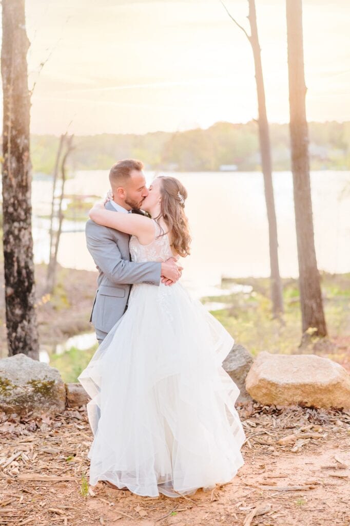 The bride and groom kiss next to one of North Carolina's lakes outside after their wedding ceremony.