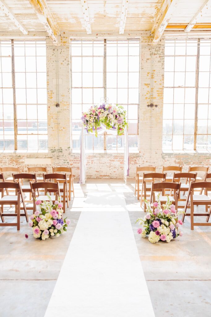 An archway and rows of chairs are set up in the Kettle Room for the wedding ceremony.