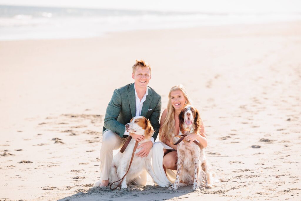 Spencer and Dave hug their dogs close on the shore for their engagement pictures on the beach.