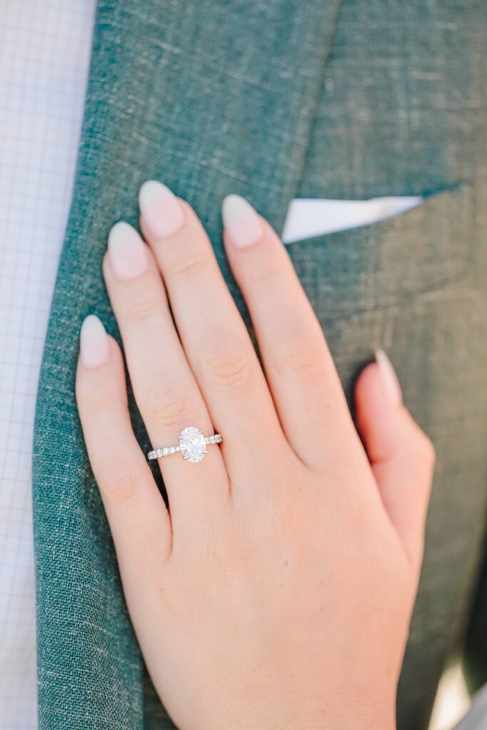 Beach engagement pictures with a silver engagement ring with an oval center stone and studded band.