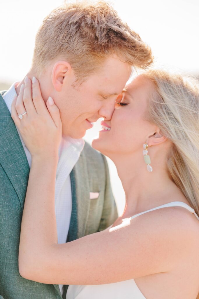 This beach engagement picture shows a close up of Spencer and Dave nuzzling noses and smiling with each other.