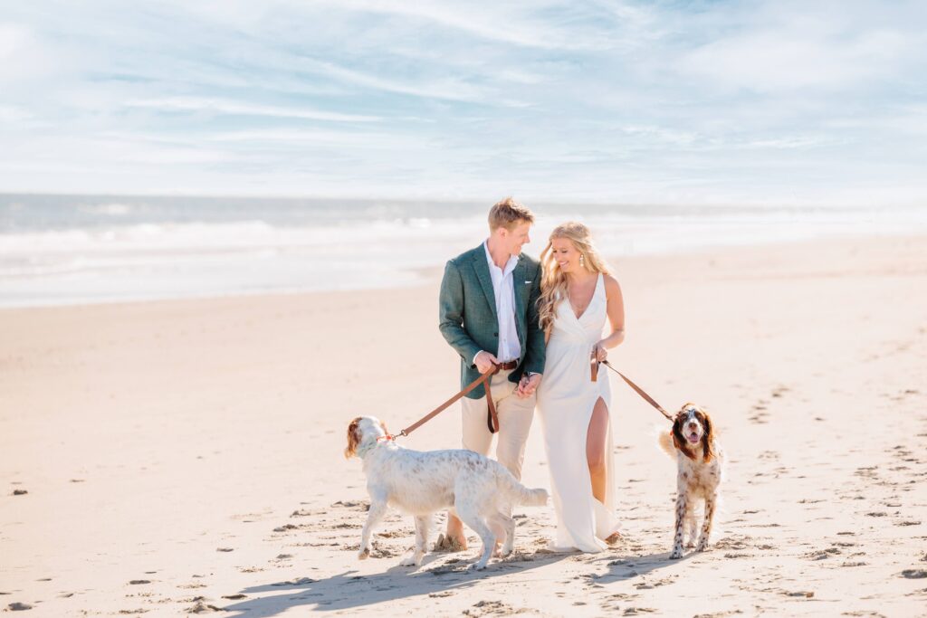 Spencer and Dave walk their two dogs on the shore during their beach engagement pictures.