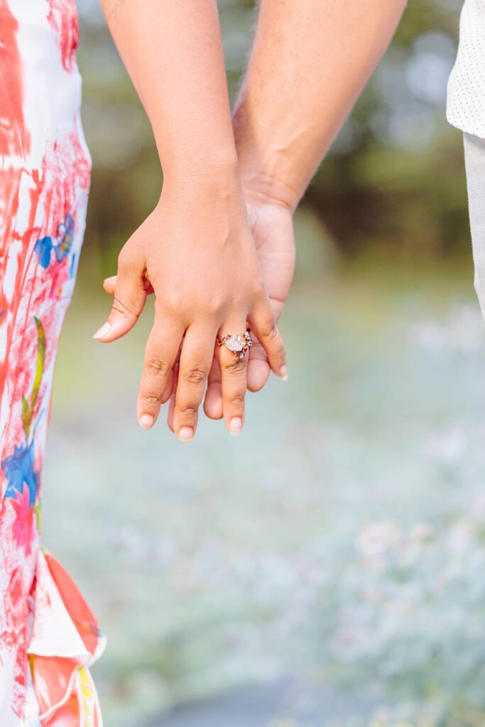 LaVianca and Shakim hold hands, and the eucalyptus field on the lavender farm in NC can be seen behind their hands.