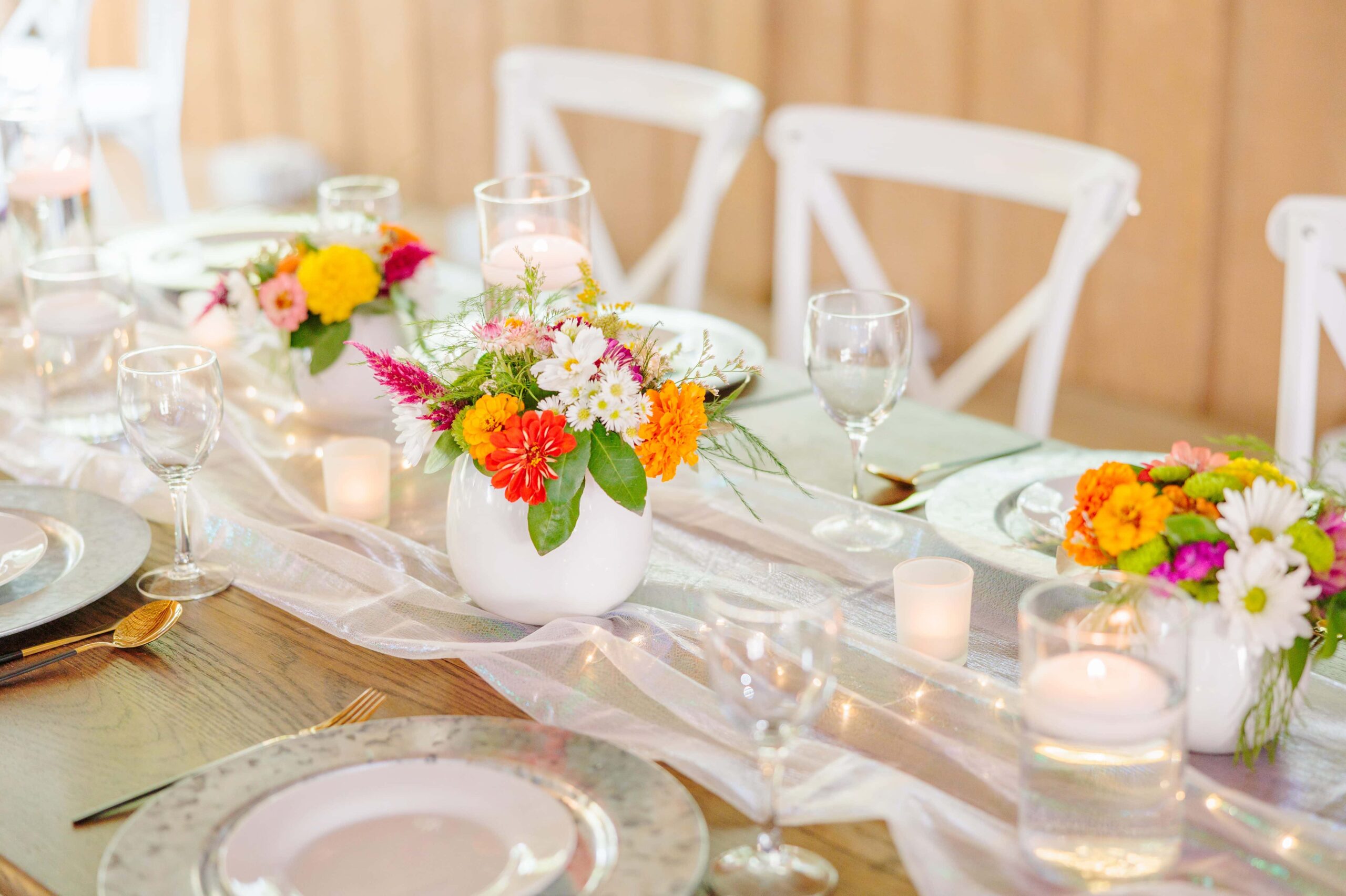 The table setting at this disco wedding had bright orange flowers and holographic fabric running down the middle.