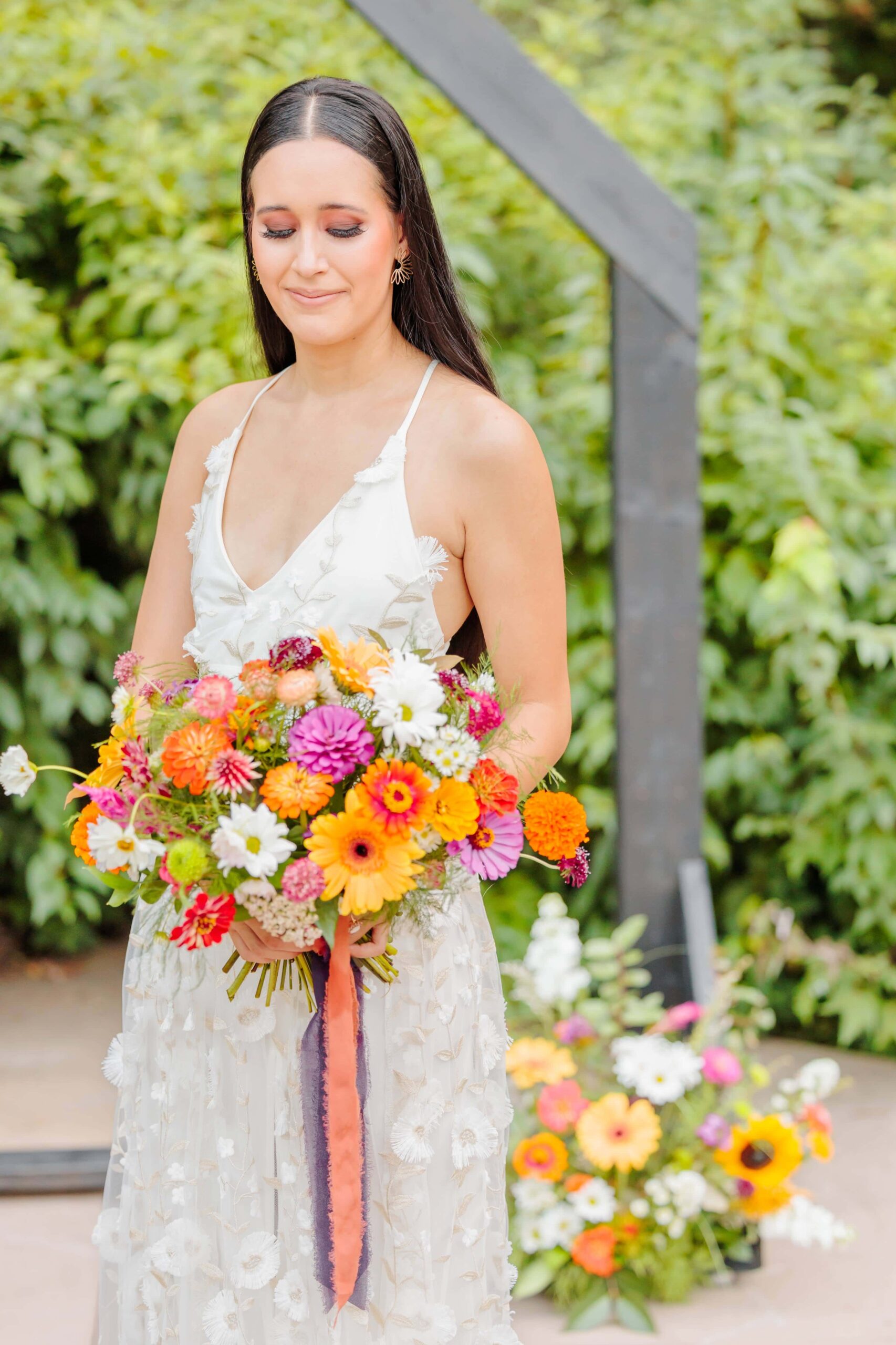 The bride looks down at her brightly colored bouquet, made to match the orange and yellow colors of her disco wedding.