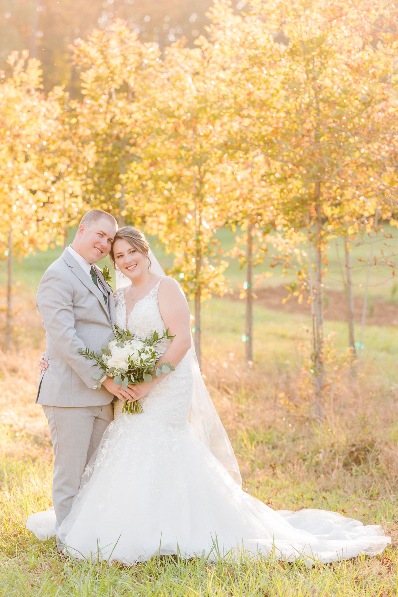 Low Meadows Estate has a row of orange and yellow tress, the light shines through them as the bride and groom smile at the camera.