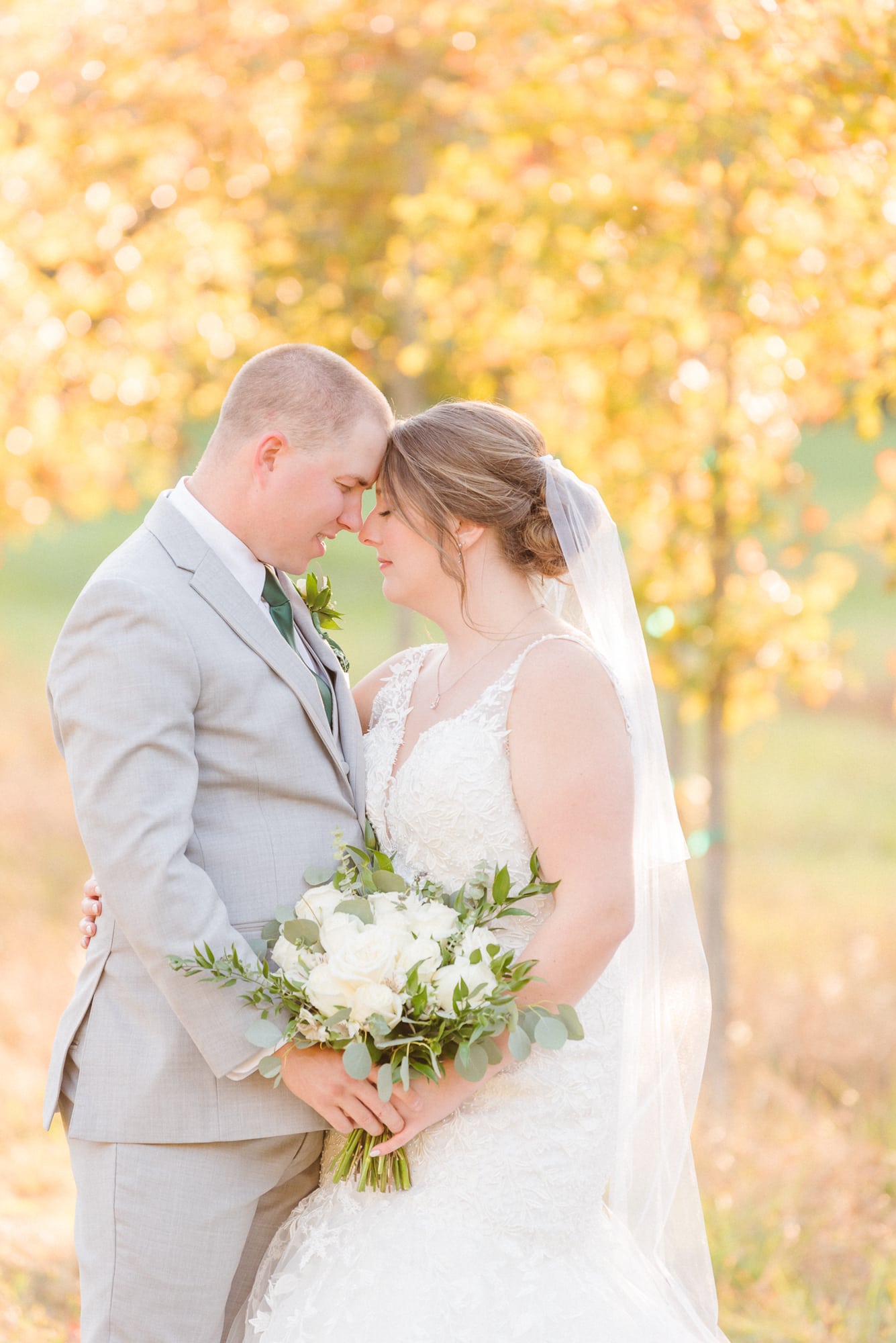 Katelynn and Alec stand nose-to-nose with golden trees behind them after their wedding at Low Meadows Estate.