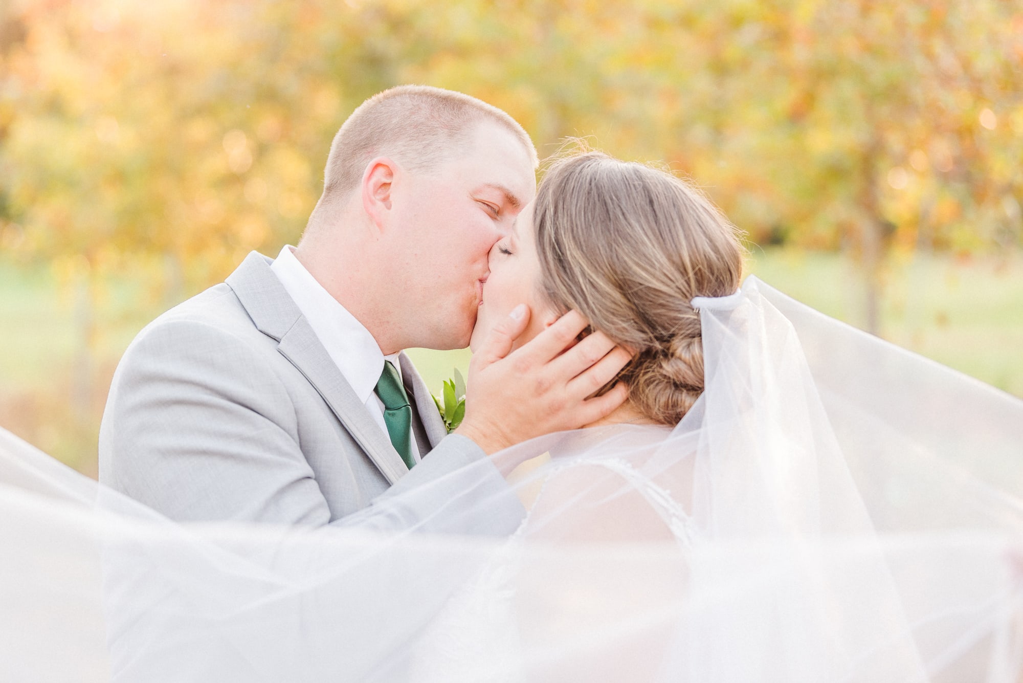 The veils swirls around the kissing couple and the fall colors of the Low Meadows Estate are seen in the background.
