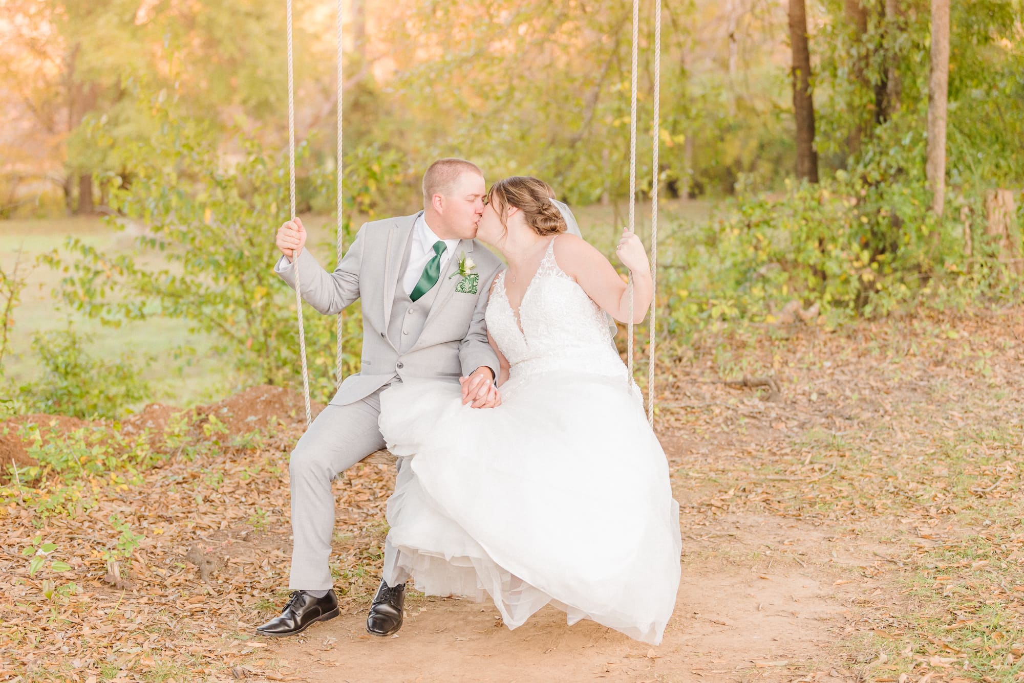 Katelynn and Alec kiss on the swinging bench on the grounds of the Low Meadows Estate wedding venue.