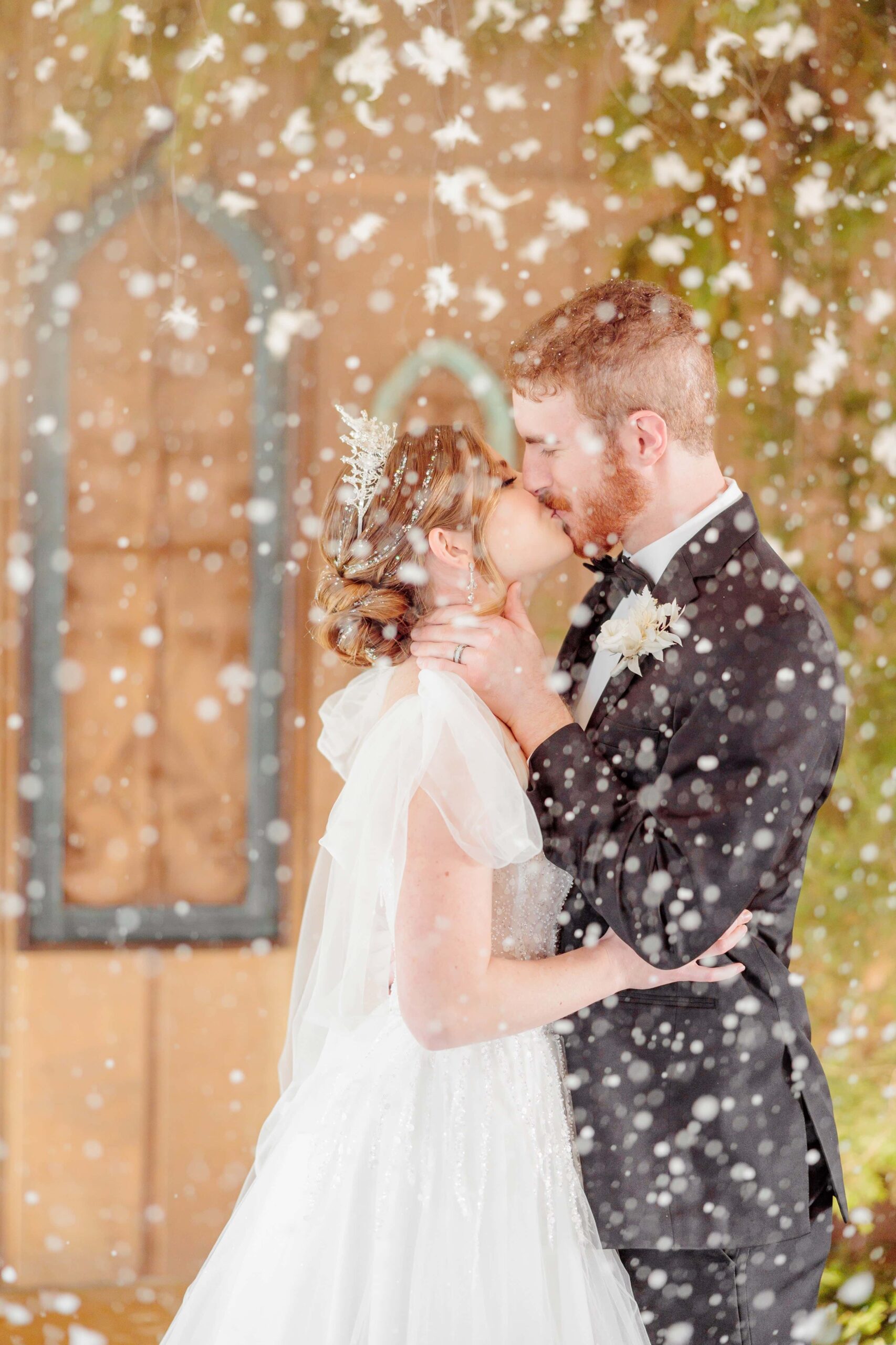 Liz and Ryan kiss while snowflakes swirl around them at this winter wonderland wedding.