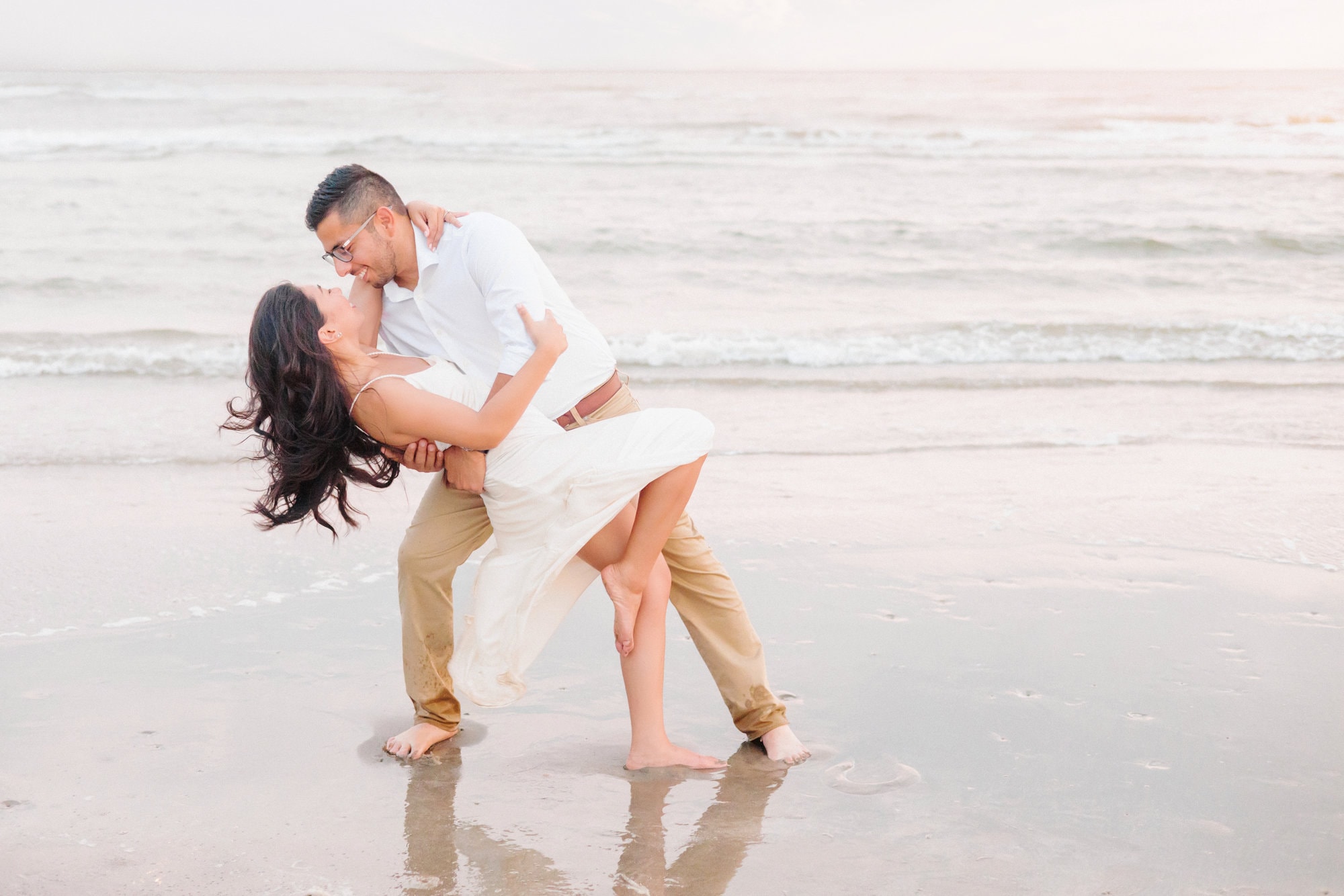 A romantic scene in front of the water where Edgar swings Carisil into a dip in front of the ocean.