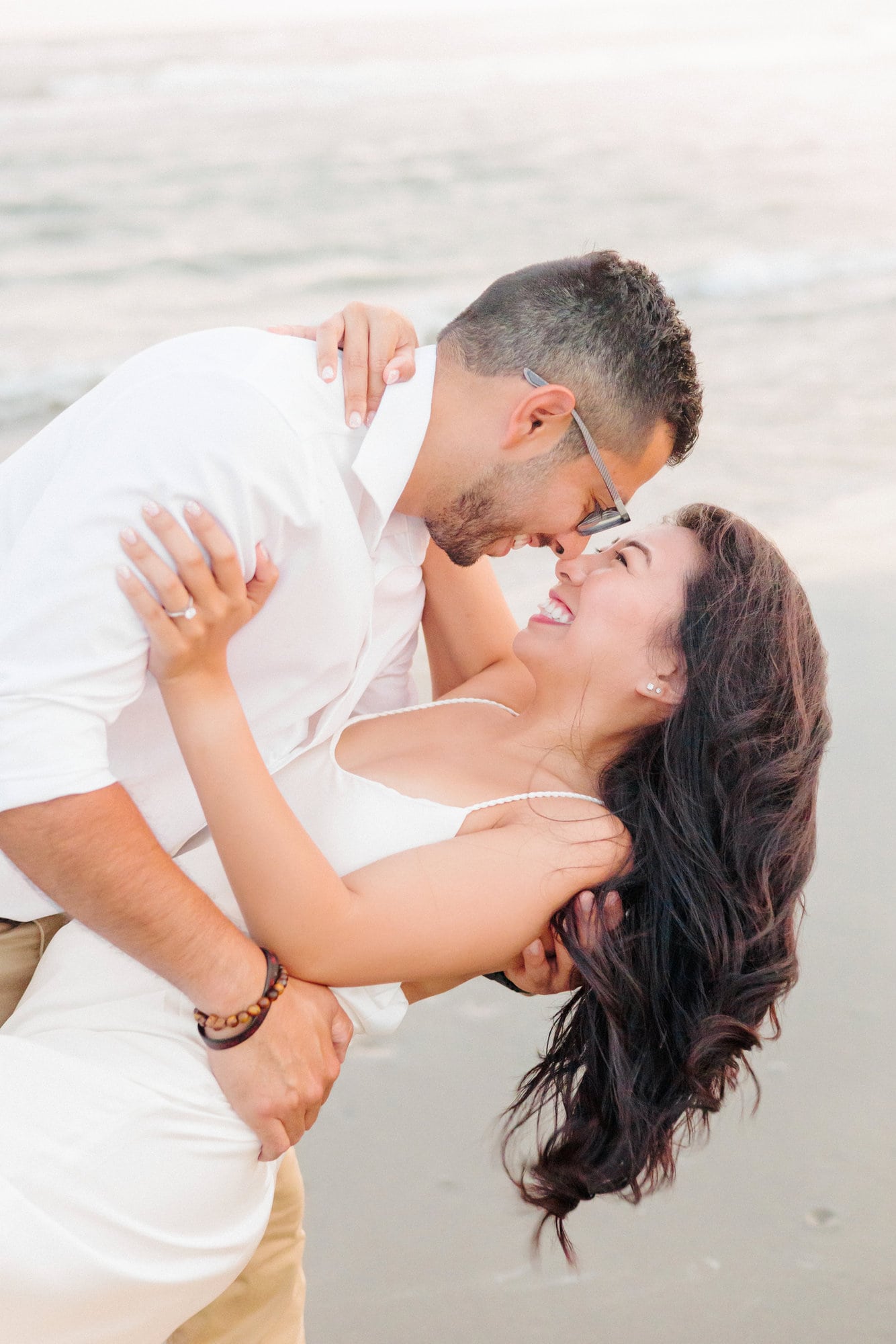 Edgar dips Carisil on the shoreline while taking engagement pictures on the beach.