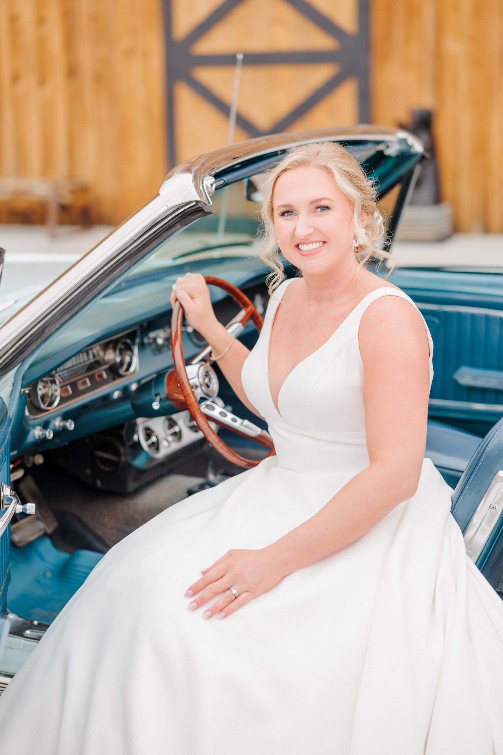 A classic bridal portrait of Bailey smiling from the front seat of her vintage car.