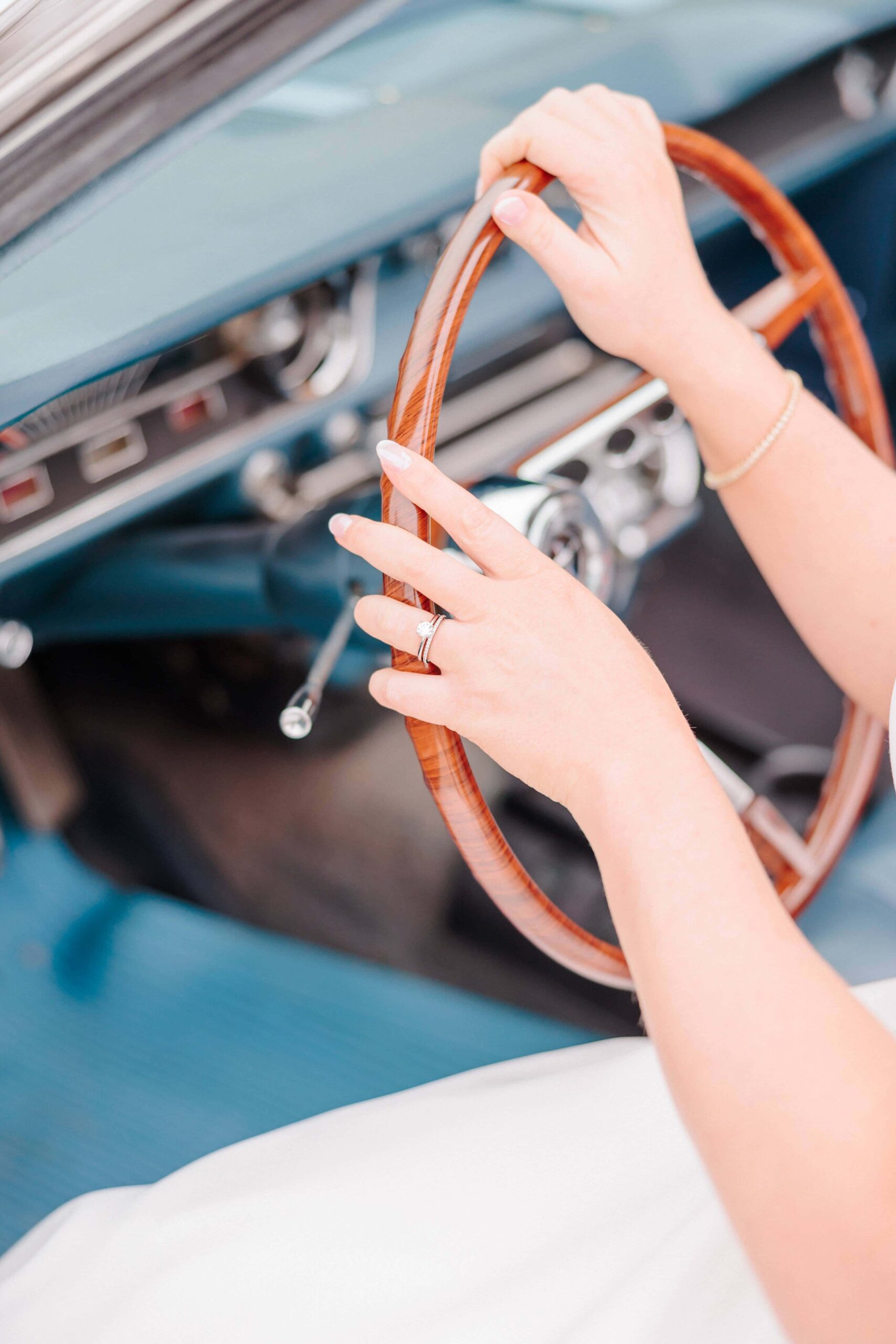 Bailey holds on to the steering wheel of her vintage car for bridal photos.